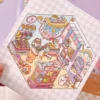 Carnet à spirales contenant 20 scènes de stickers isométrique 3D à composer soi-même sur le thème des boutiques kawaii et mignonnes. Activité créative pour adulte pour gérer le stress.