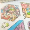 Carnet à spirales contenant 20 scènes de stickers isométrique 3D à composer soi-même sur le thème des boutiques kawaii et mignonnes. Activité créative pour adulte pour gérer le stress.